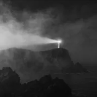 Original photograph: lighthouse in fog with a bright beam, black and white